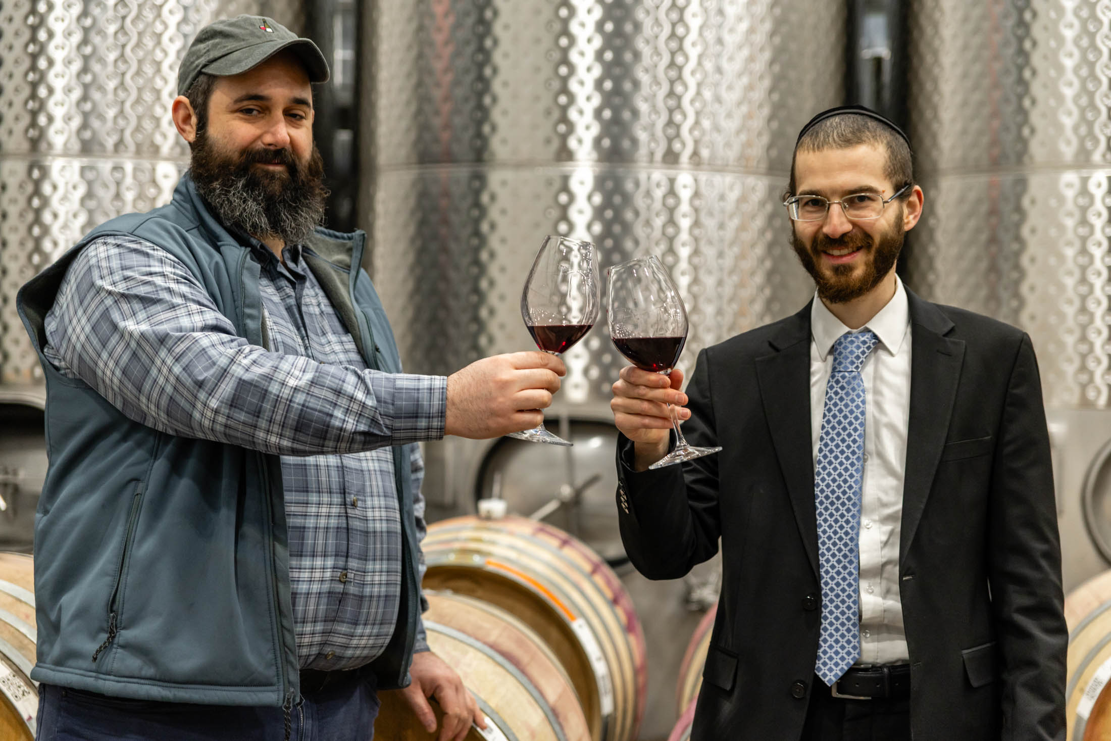 Two men clinking wine glasses in a winery