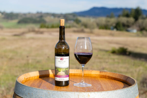 Wine bottle and glass on wooden barrel