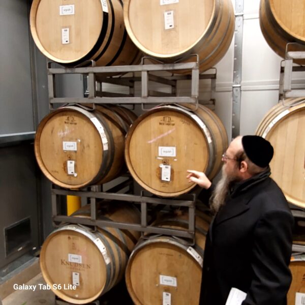 Person pointing at stacked wooden barrels
