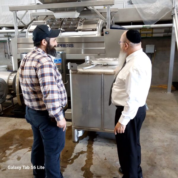 Two men inspecting stainless steel industrial equipment